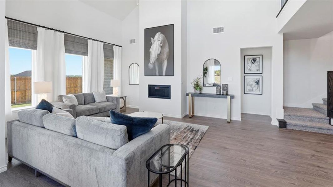 Living area with a glass covered fireplace, dark wood finished floors, and vaulted ceiling