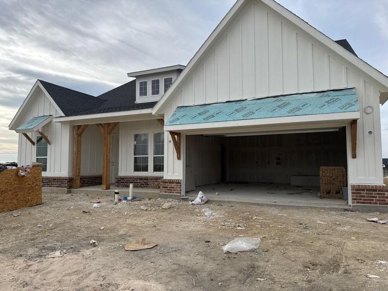 Property under construction with board and batten siding, brick siding, a garage, and a shingled roof Property under construction with board and batten siding, brick siding, a garage, and a shingled roof
