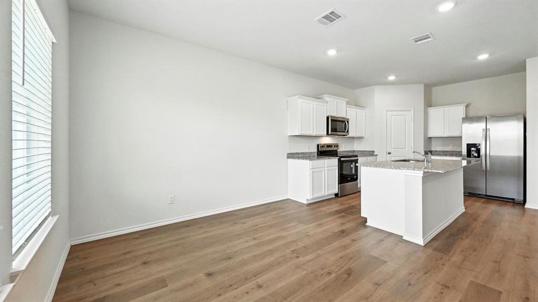 Kitchen featuring stainless steel appliances, healthy amount of natural light, white cabinets, an island with sink, and recessed lighting