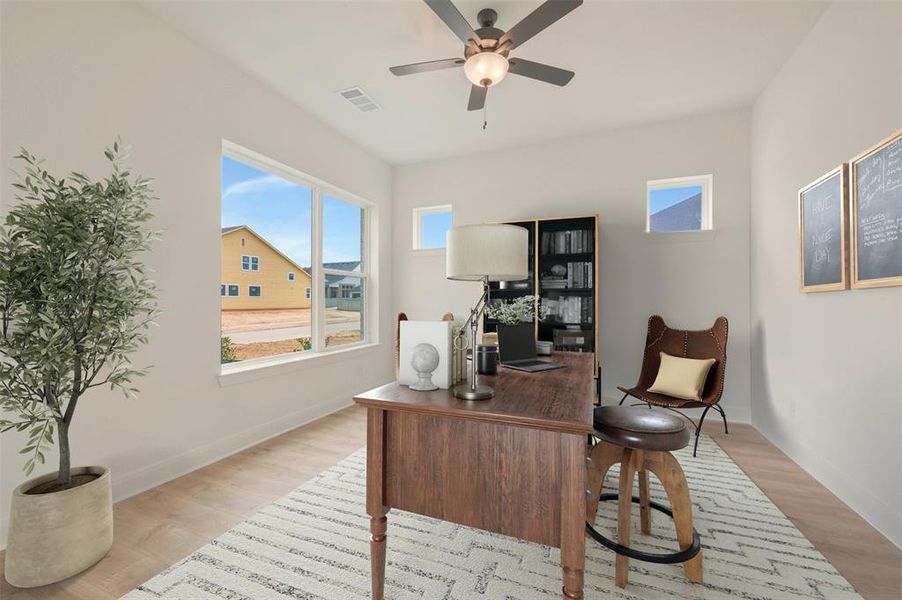 Bright interior space featuring light wood-finish flooring, a contemporary ceiling fan with integrated lighting, and multiple windows