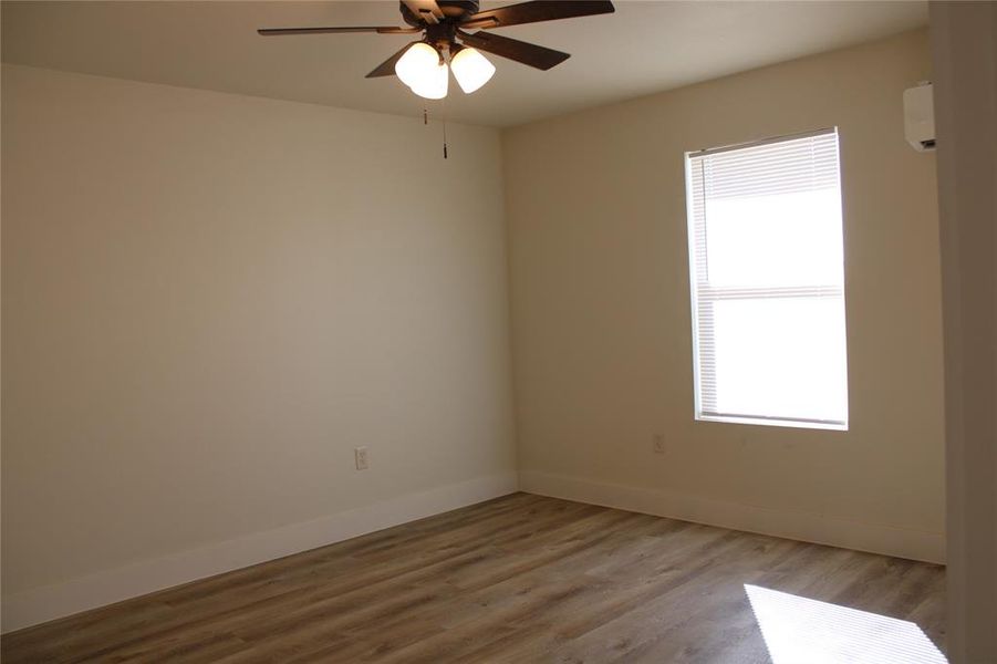 Spare room with wood finished floors, a ceiling fan, and a wall unit AC