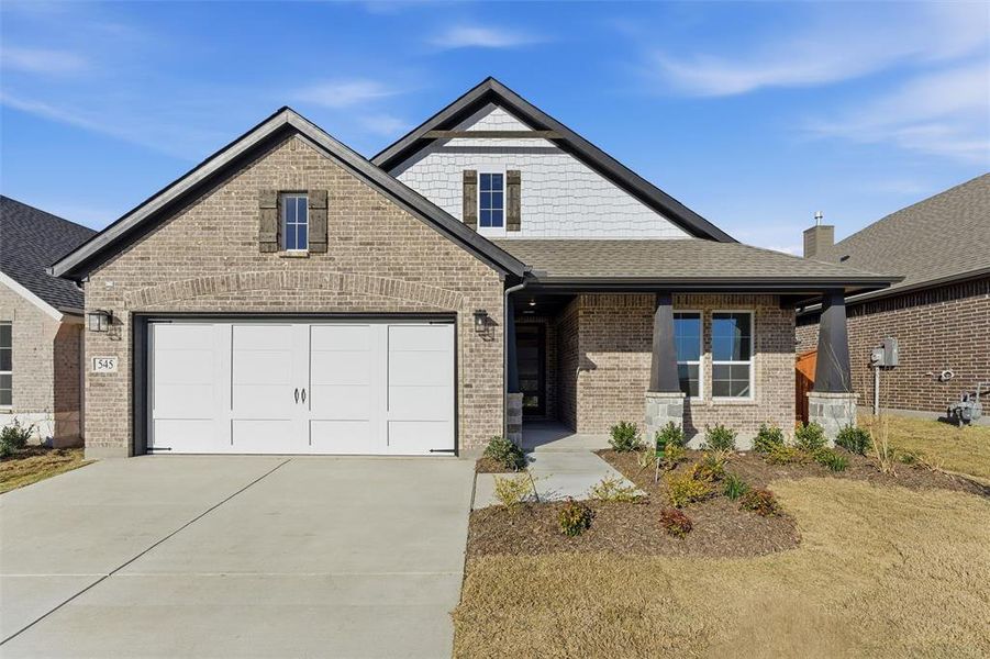 View of front of property featuring a porch, concrete driveway, a garage, brick siding, and a shingled roof