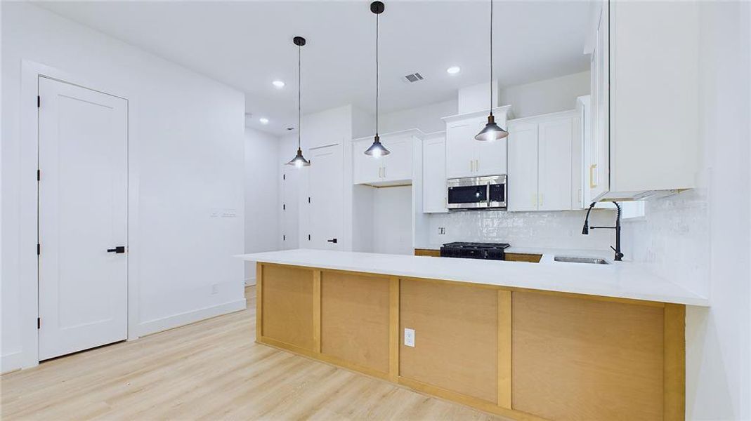 Alternate view of the kitchen. The door on the left opens to a thoughtfully designed additional mini-pantry, perfect for spices, condiments, and additional storage. The door in the corner provides direct access to the two-car garage, offering convenient access for bringing groceries straight into the kitchen.