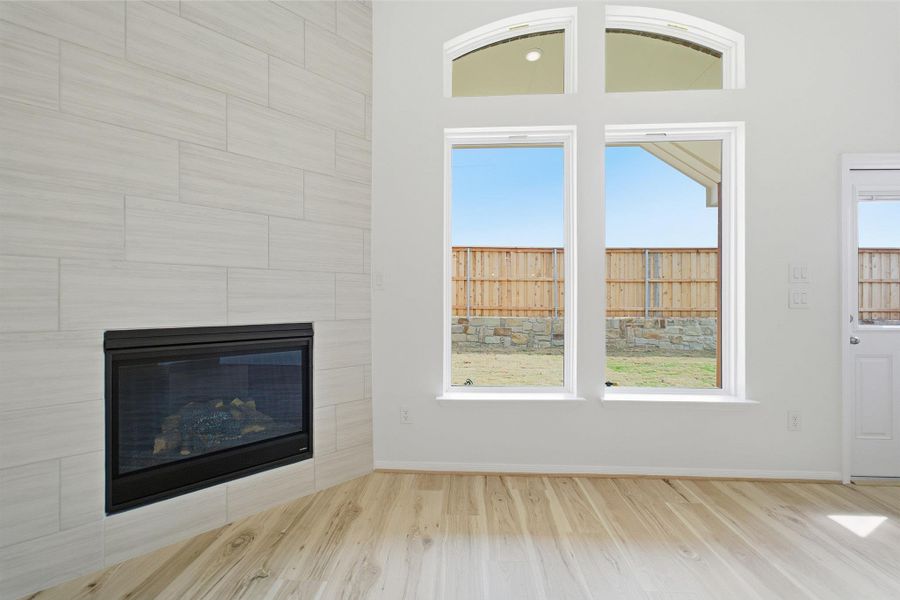 Unfurnished living room featuring light wood finished floors and a tile fireplace