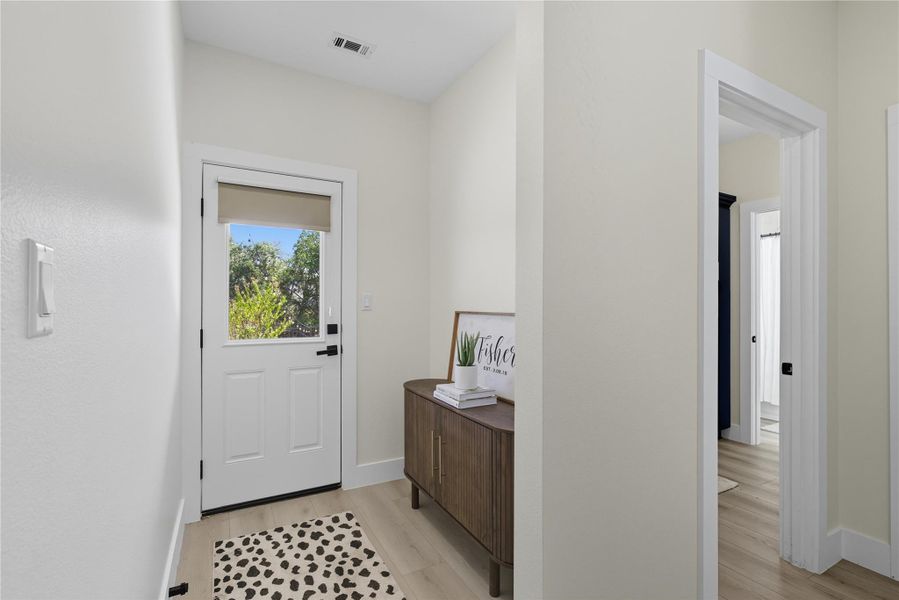 Doorway with wood finished floors and baseboards