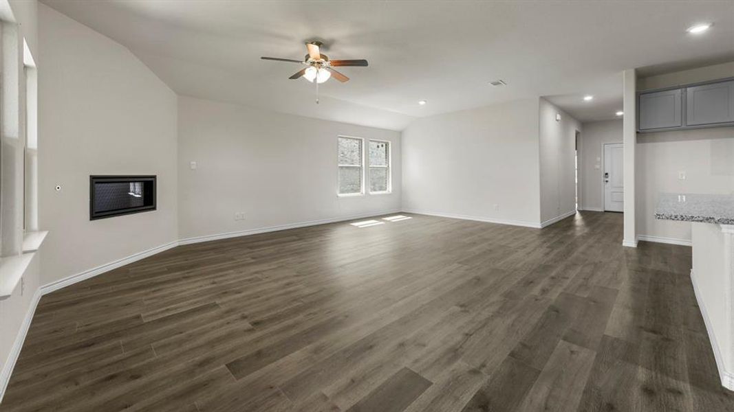 Spacious living area featuring plank flooring, vaulted ceilings, and a modern fireplace