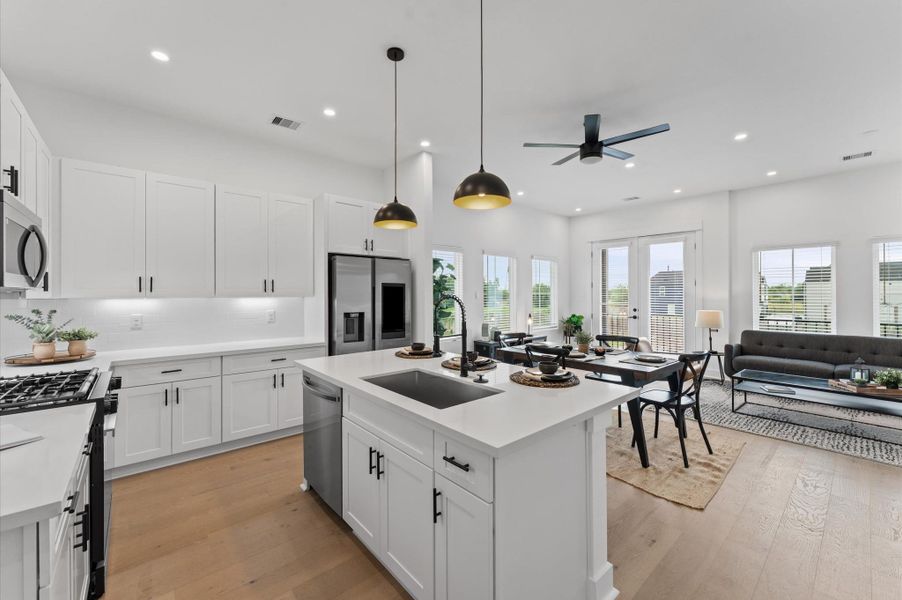 This centrally positioned kitchen island serves as a stylish anchor within the open-concept layout, offering clear sightlines to the dining area, living space, and the balcony beyond. Its placement encourages seamless interaction, whether prepping meals or entertaining guests, while natural light pours in through the nearby French doors. The island’s sleek design and functional surface make it a hub of activity tying together comfort and sophistication.