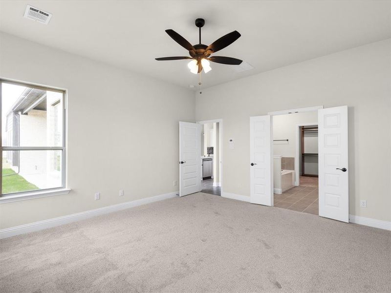 Unfurnished bedroom with light colored carpet, a ceiling fan, and ensuite bathroom