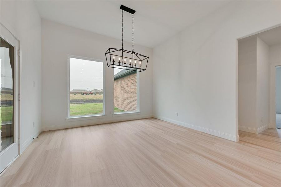 Unfurnished dining area with light hardwood / wood-style flooring and a chandelier