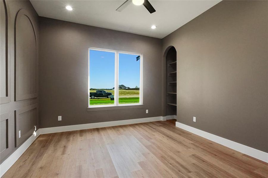 Spare room with light wood-style floors, a ceiling fan, recessed lighting, built in shelves, and arched walkways Spare room with light wood-style floors, a ceiling fan, recessed lighting, built in shelves, and arched walkways