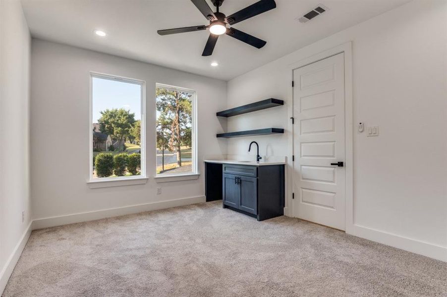 Bar area with open shelves, light carpet, ceiling fan, recessed lighting, and dark cabinetry Bar area with open shelves, light carpet, ceiling fan, recessed lighting, and dark cabinetry