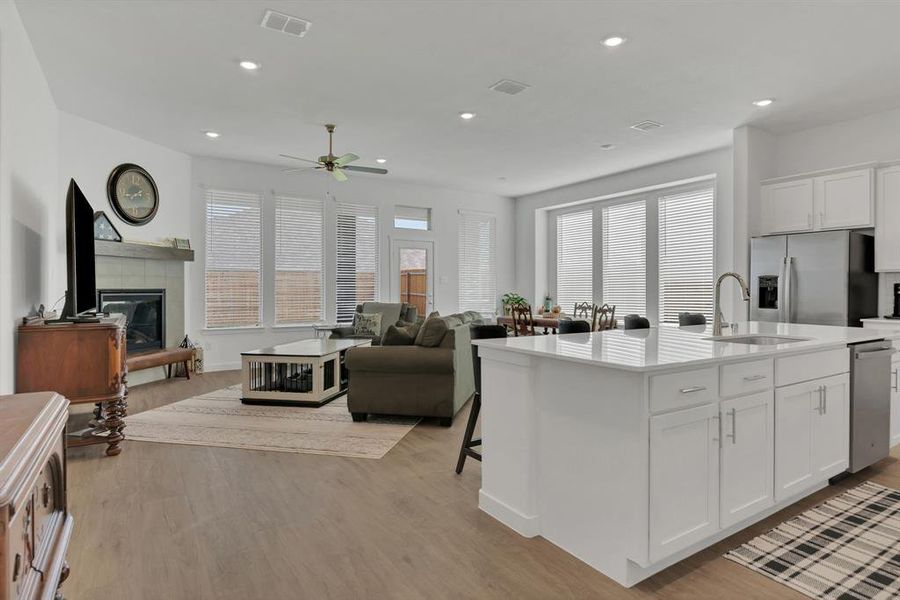 Kitchen with white cabinetry, a breakfast bar area, a kitchen island with sink, light wood-type flooring, and open floor plan