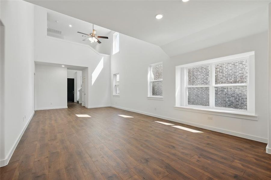 Unfurnished living room featuring dark wood-style floors, recessed lighting, high vaulted ceiling, and a ceiling fan