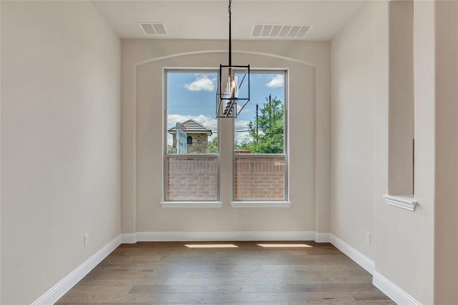 Empty room featuring a notable chandelier and light hardwood / wood-style flooring