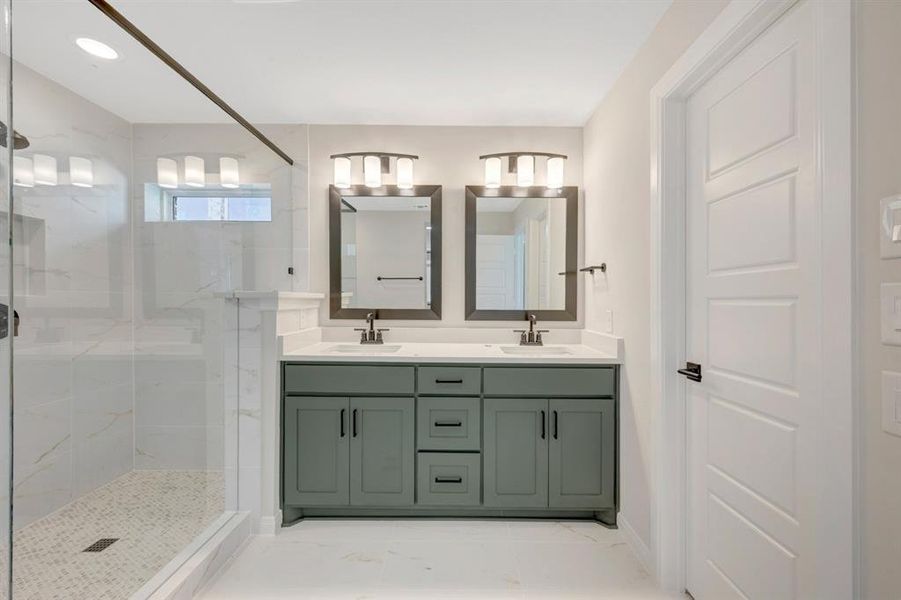 Bathroom featuring double vanity and a marble finish shower