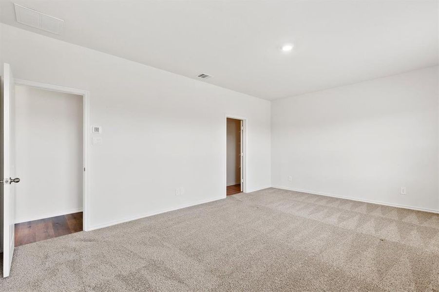 Spacious room featuring neutral carpeting, a recessed ceiling light, and white painted walls