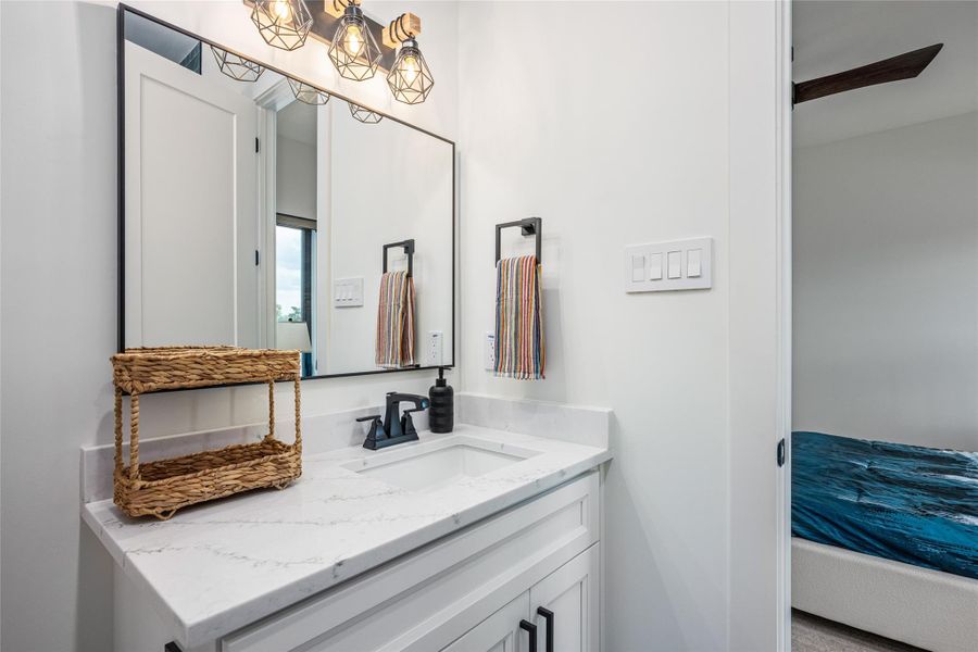 The en suite bath features a wide soaking tub, porcelain backsplash, quartz countertops, custom mirrors, and ambient vanity lighting