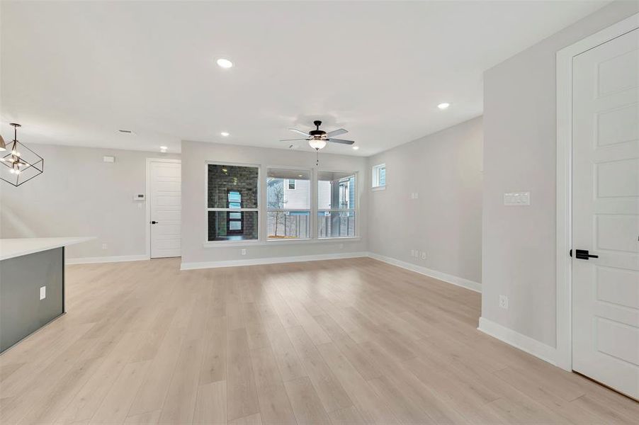Unfurnished living room with ceiling fan, light wood-style floors, and a chandelier