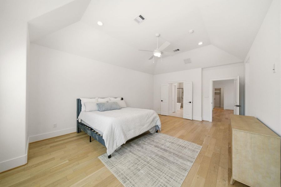 Spacious primary bedroomshowcasing elevated ceilings,expansive wall space, andseamless access to the en-suitebath and closet areas. (Photo of a previous build, similar finishes.)