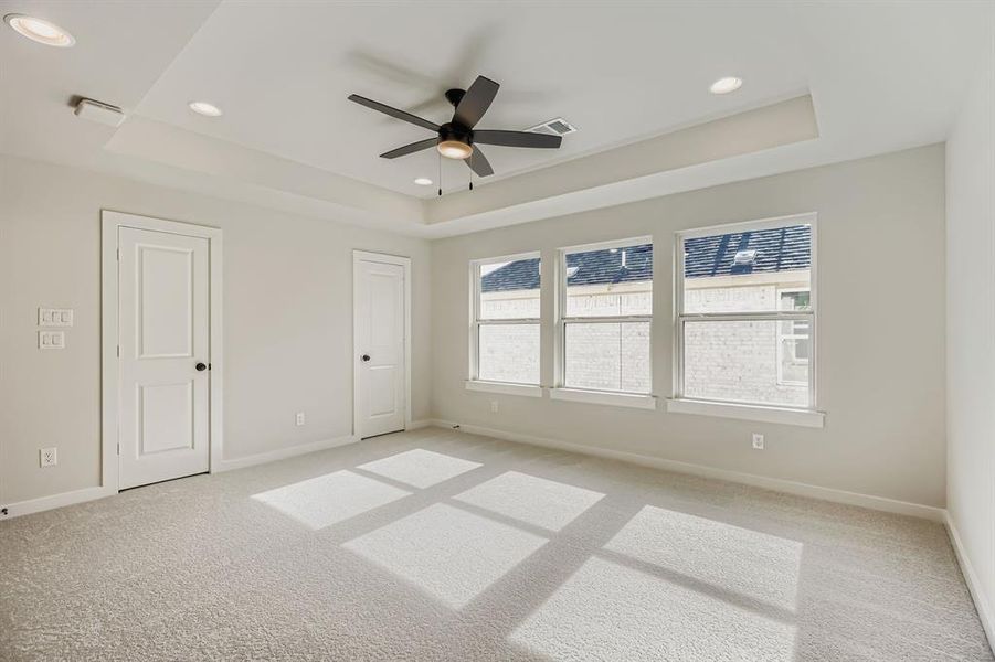 Spare room with a raised ceiling, ceiling fan, light colored carpet, and recessed lighting