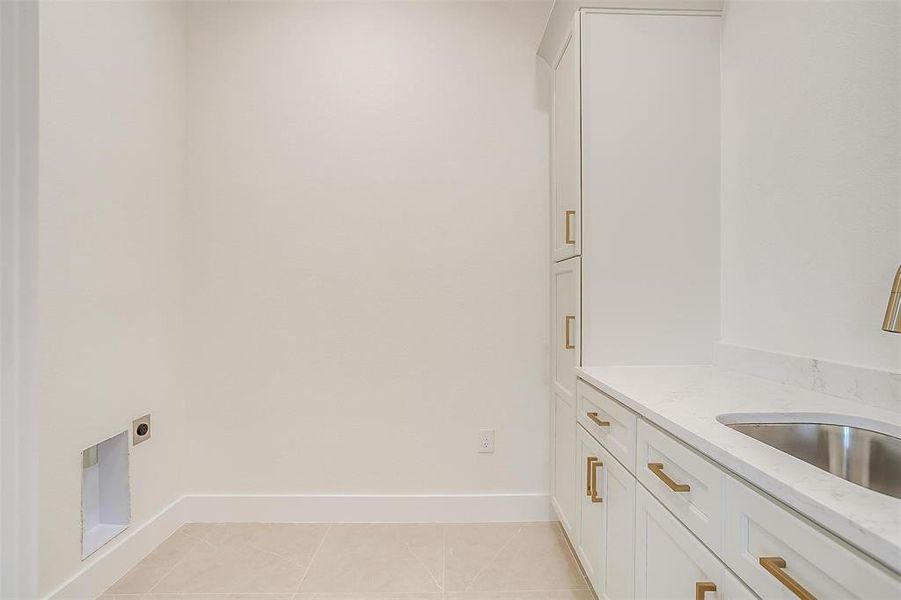 Washroom featuring cabinets, light tile patterned flooring, and hookup for an electric dryer