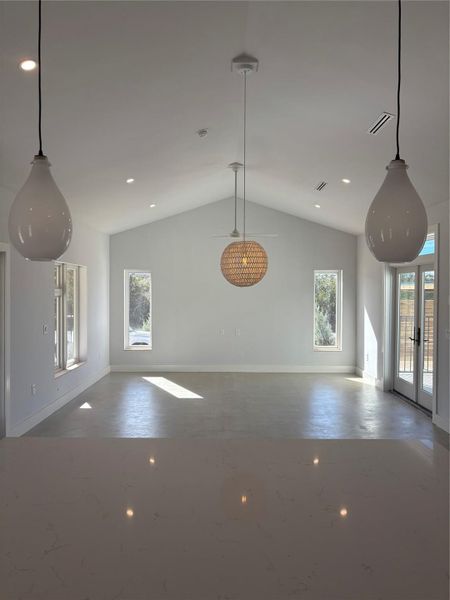 Unfurnished living room with lofted ceiling, french doors, and concrete flooring