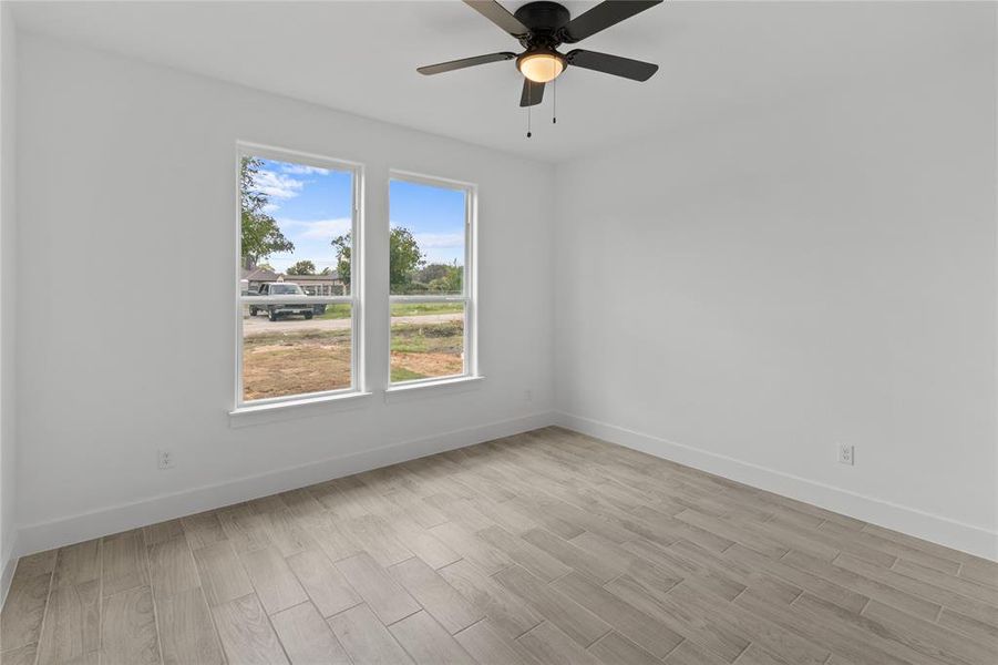 Empty room featuring a wealth of natural light, ceiling fan, and light wood-type flooring