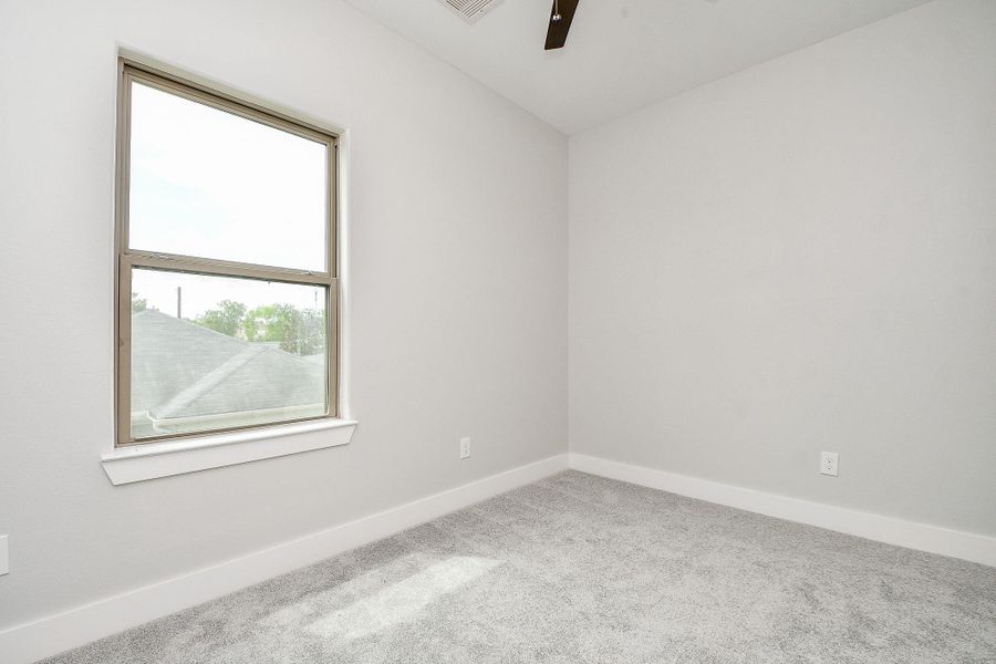 This is a bright, large secondary bedroom with a large window, plush carpeting, and a modern ceiling fan, offering a clean canvas for personalization. This is a bright, large secondary bedroom with a large window, plush carpeting, and a modern ceiling fan, offering a clean canvas for personalization.