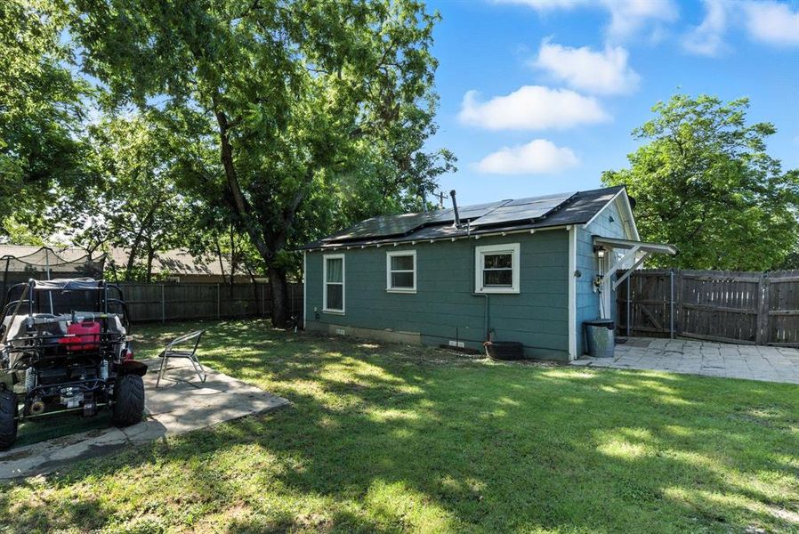 Back of house featuring a patio area, solar panels, a fenced backyard, and a gate