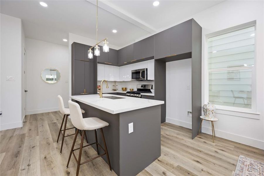 Here is a view of the kitchen and the entryway from the living room. The island is a great place to gather around with friends and family.