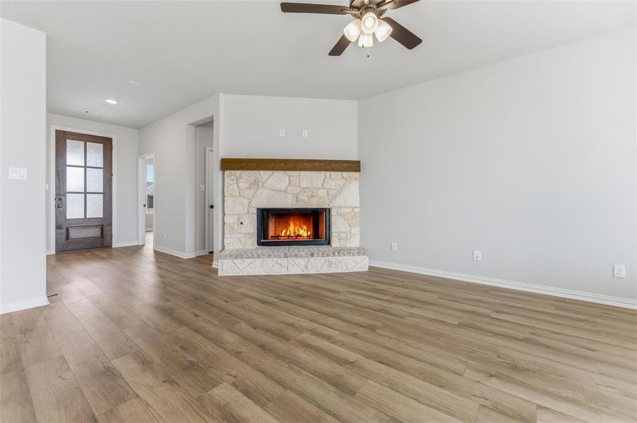 Unfurnished living room with a fireplace, ceiling fan, and wood finished floors