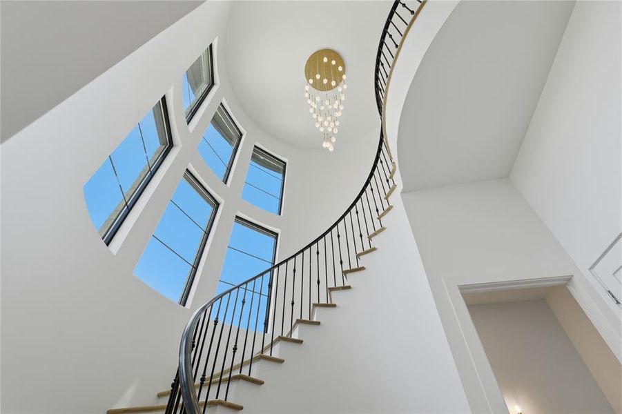 Grand curved staircase with wrought iron balusters and hardwood treads