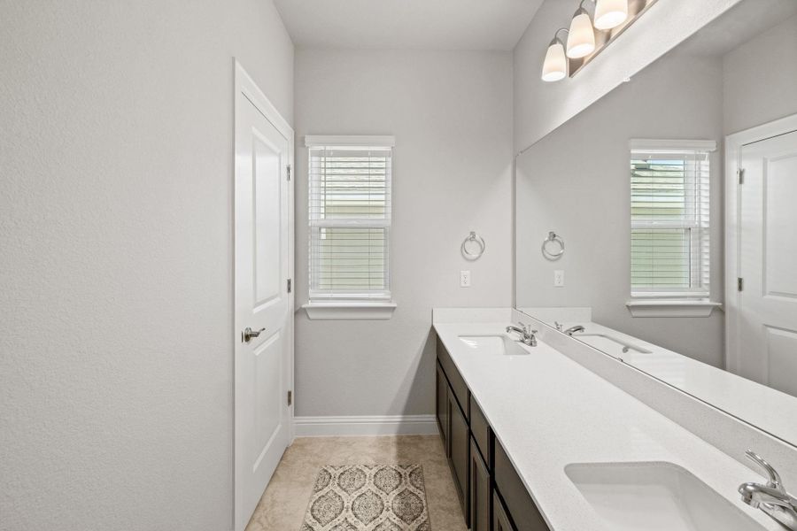 Bathroom featuring double vanity, baseboards, and a sink Bathroom featuring double vanity, baseboards, and a sink