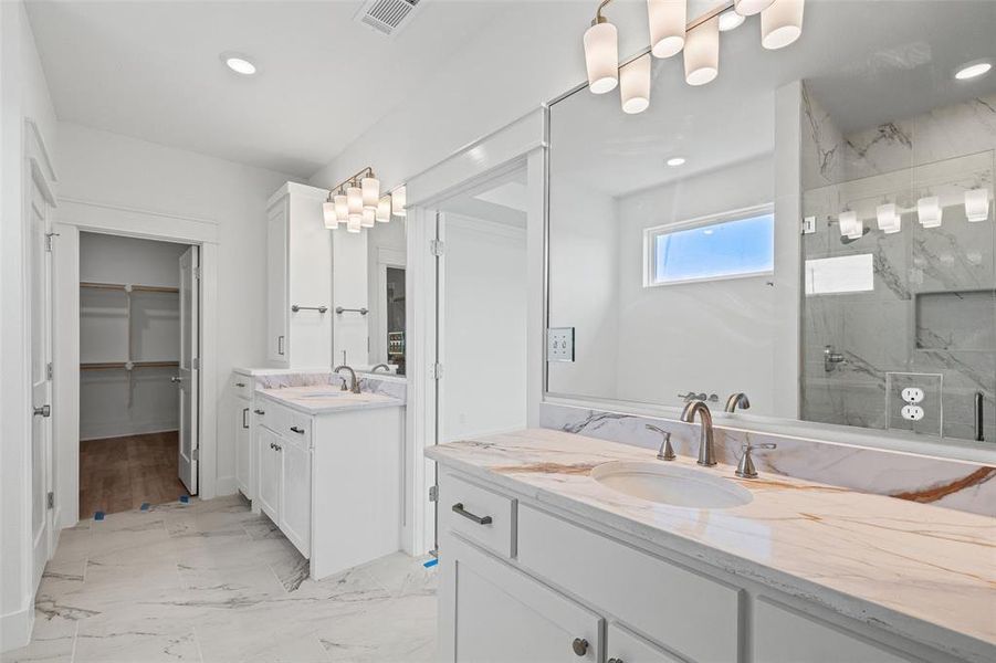 Bathroom featuring dual white vanities with marble countertops, undermount sinks, and brushed nickel fixtures