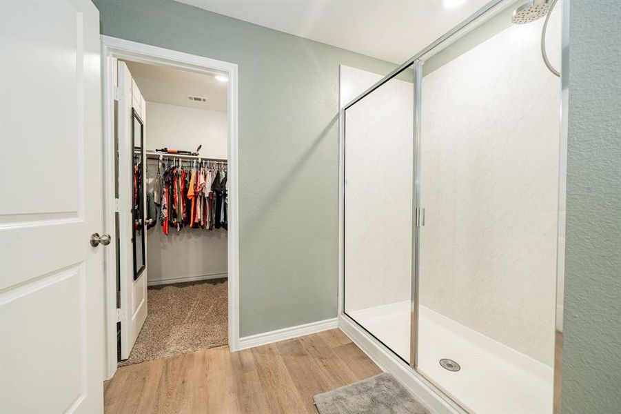 Full bath featuring a walk in closet, a stall shower, light wood-style floors, and recessed lighting Full bath featuring a walk in closet, a stall shower, light wood-style floors, and recessed lighting