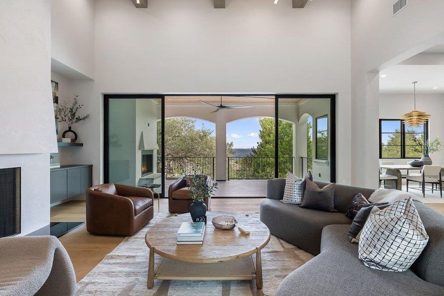 Spacious living area featuring high vaulted ceilings, light wood-finish flooring, and a stone-clad fireplace