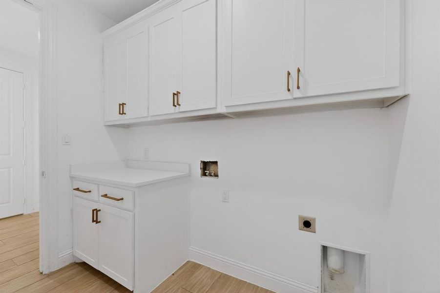 White shaker cabinetry with bronze hardware, white countertop, and wood-finish flooring White shaker cabinetry with bronze hardware, white countertop, and wood-finish flooring