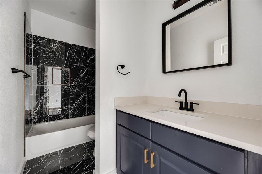 Bathroom featuring vanity, dark marble finish floors, and bathtub / shower combination