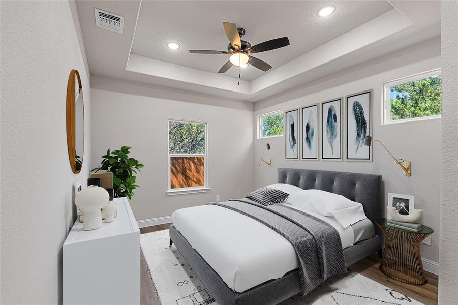 Bedroom featuring light wood-type flooring, ceiling fan, and a tray ceiling