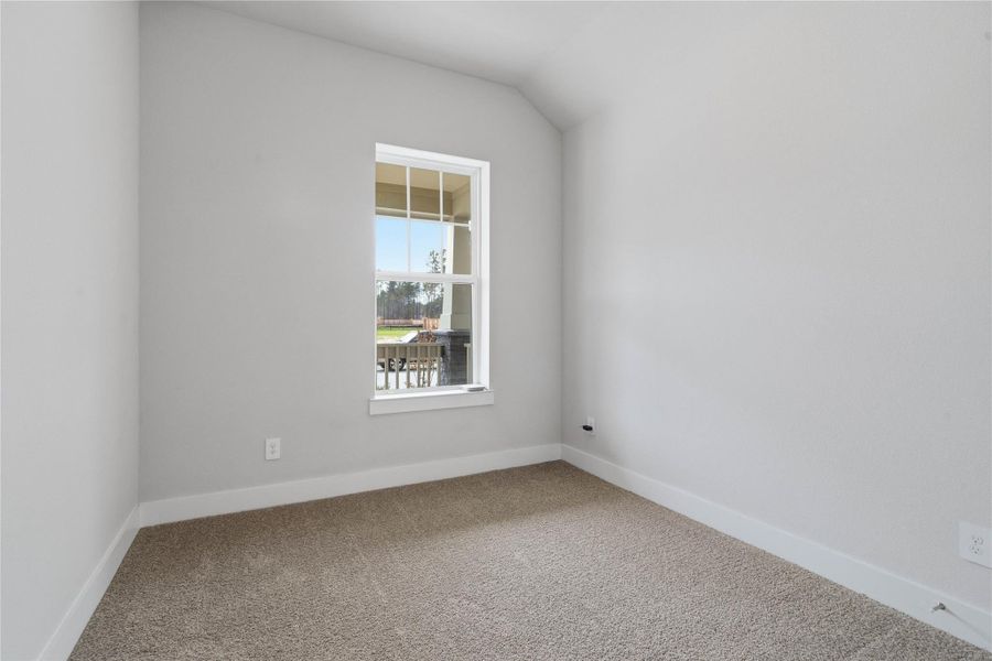Step into this bright and airy secondary bedroom which features plush carpet flooring, ample sized closet space, and a large window which illuminate the room's sloped ceiling and neutral tones, creating a cheerful and airy environment.