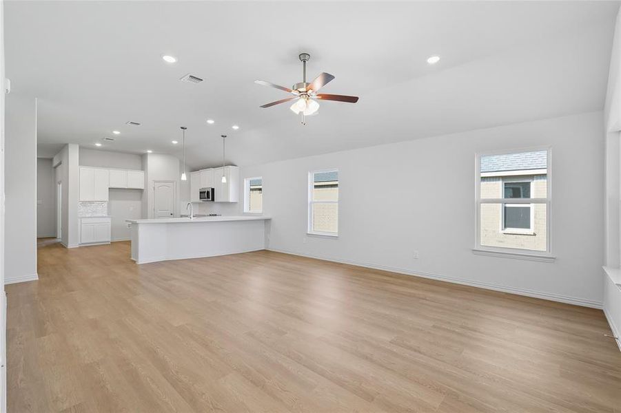 Unfurnished living room with plenty of natural light, light wood-style flooring, vaulted ceiling, ceiling fan, and recessed lighting Unfurnished living room with plenty of natural light, light wood-style flooring, vaulted ceiling, ceiling fan, and recessed lighting