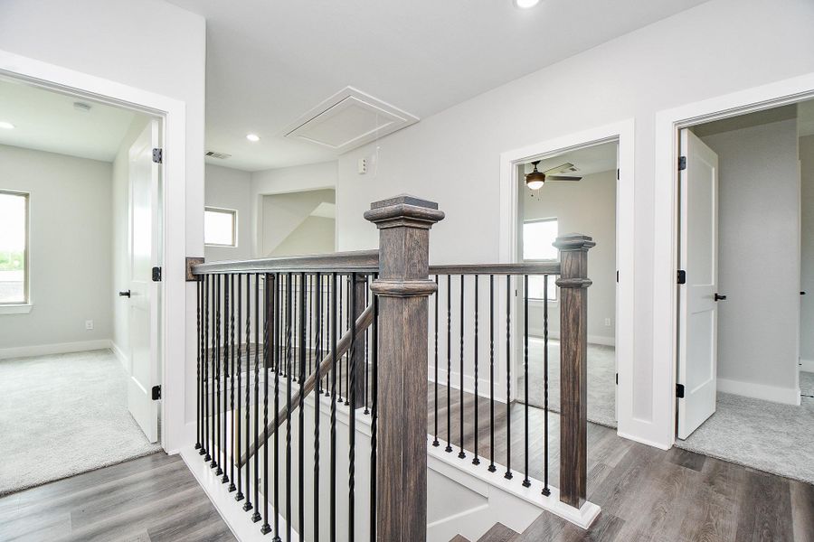 This photo showcases an upper-level interior space with a neutral color palette, featuring an open landing with dark-stained wooden railing, plush carpeting in the adjacent room, and modern flooring in the hallway. Multiple doors suggest access to several rooms, and the space is well-lit with natural and artificial light. This photo showcases an upper-level interior space with a neutral color palette, featuring an open landing with dark-stained wooden railing, plush carpeting in the adjacent room, and modern flooring in the hallway. Multiple doors suggest access to several rooms, and the space is well-lit with natural and artificial light.