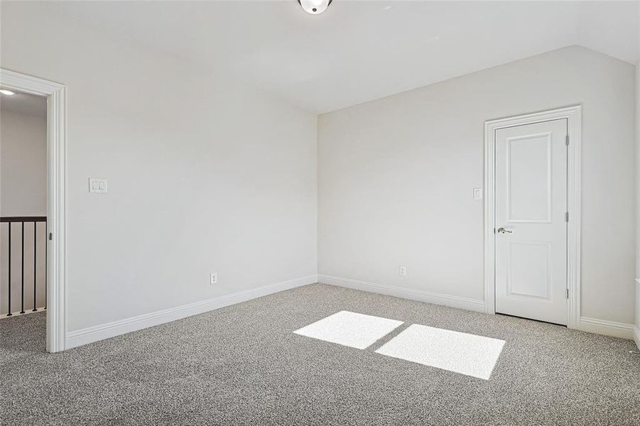 Carpeted empty room with vaulted ceiling