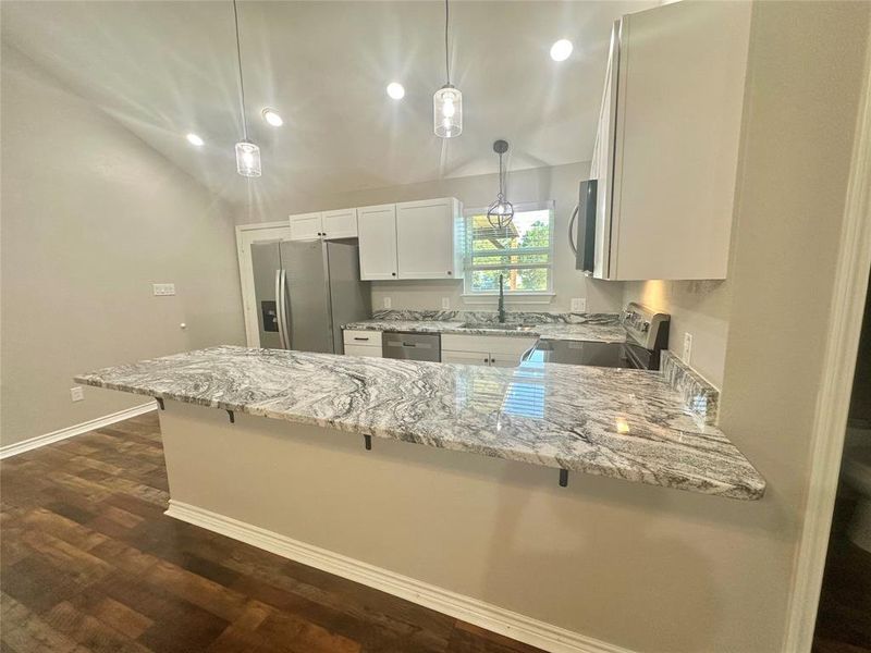 Upstairs Kitchen with stainless steel appliances, granite counters, a peninsula, a breakfast bar area, and LVP floors Upstairs Kitchen with stainless steel appliances, granite counters, a peninsula, a breakfast bar area, and LVP floors
