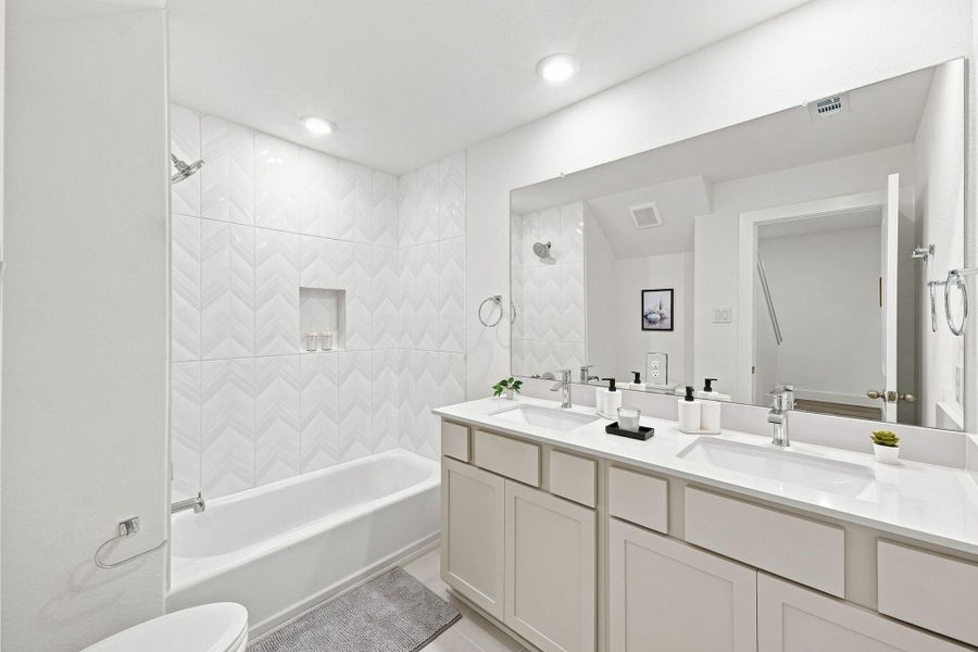 Secondary bathroom featuring a double-sink vanity, modern fixtures, and a tub/shower combination. Secondary bathroom featuring a double-sink vanity, modern fixtures, and a tub/shower combination.