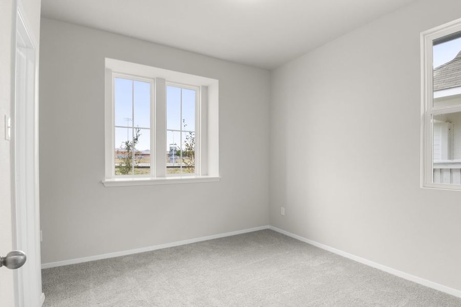Image of second bedroom with light carpet and floors with a window