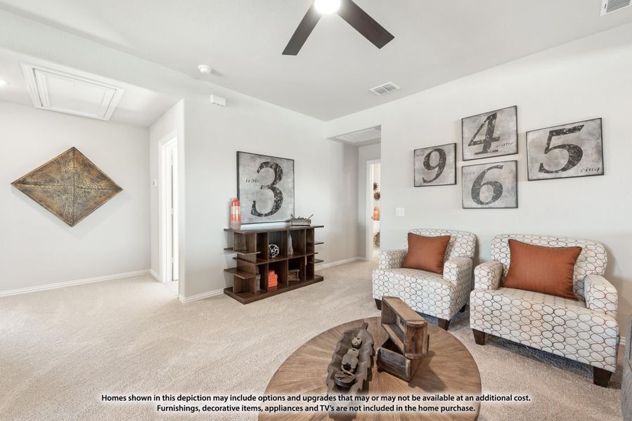Sitting room with carpet, ceiling fan, two accent chairs, open shelving unit, and decorative number wall art