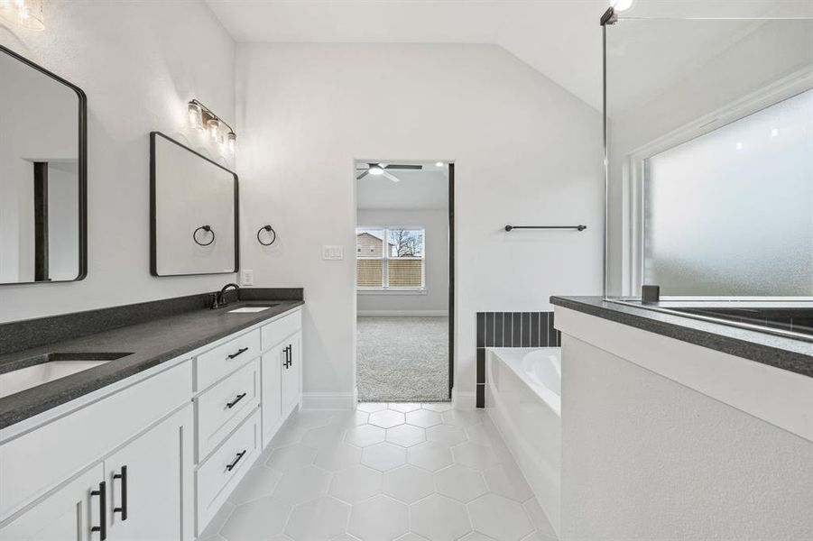 Bathroom featuring a garden tub, light tile patterned floors, lofted ceiling, double vanity, and a ceiling fan