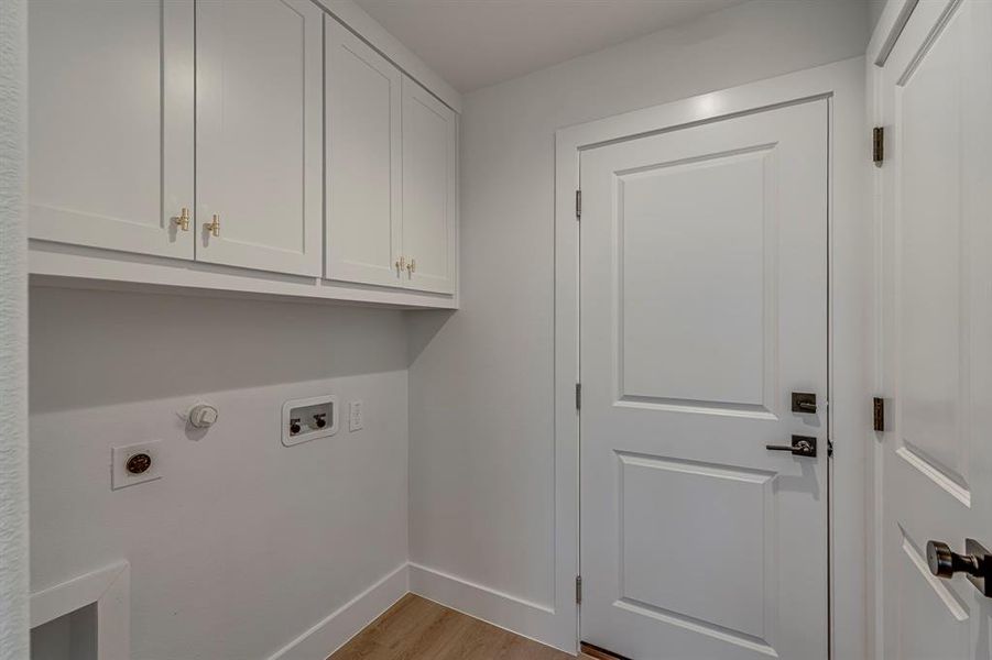 Clothes washing area featuring cabinet space, baseboards, wood finished floors, hookup for a washing machine, and hookup for an electric dryer