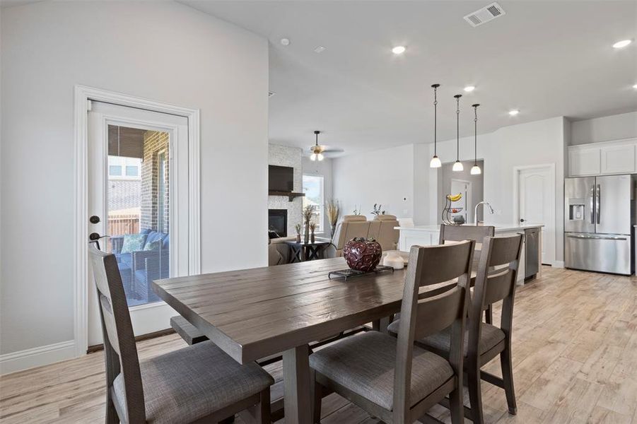 Dining room featuring light hardwood / wood-style floors, a stone fireplace, plenty of natural light, and ceiling fan